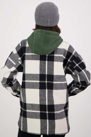 A person with long hair is wearing a gray knit beanie and a black-and-white checkered Swanndri Anchorage v2 Wool Shirt Jacket with a green hood. They are standing with their back to the camera, hands on their hips.