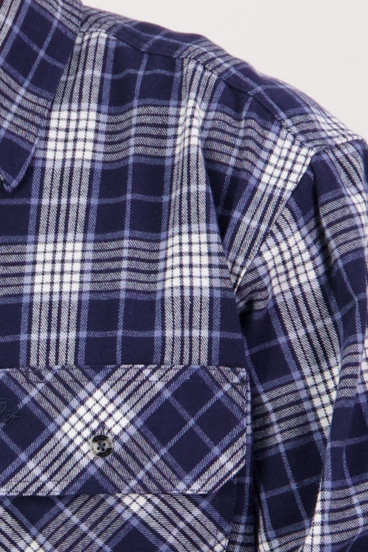 Close-up of the Swanndri Barn Shirt in blue and white plaid, showing its heritage style, front chest pocket, button, and part of the collar—ideal for layering in winter.