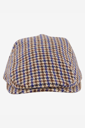 The Swanndri Bristol Flat Cap showcases a classic houndstooth pattern in brown, beige, and blue tones. Made from a quality wool blend, this cap is an ideal outdoor accessory and is displayed against a white background.