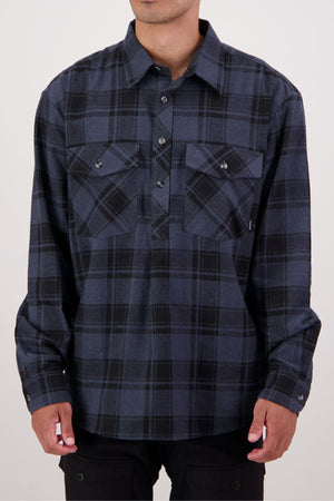 A person wearing the Swanndri Egmont Flannelette Twin Pack—featuring a long-sleeve, dark blue and black plaid heavy flannelette shirt with two chest pockets—stands against a plain background, face not visible.