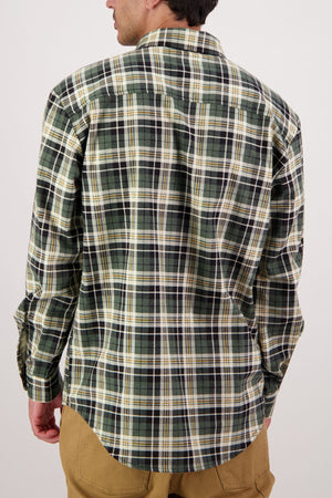 A man is seen from behind wearing a Swanndri Egmont Flannelette Twin Pack shirt in green, black, and white plaid with tan pants, standing against a plain light background.