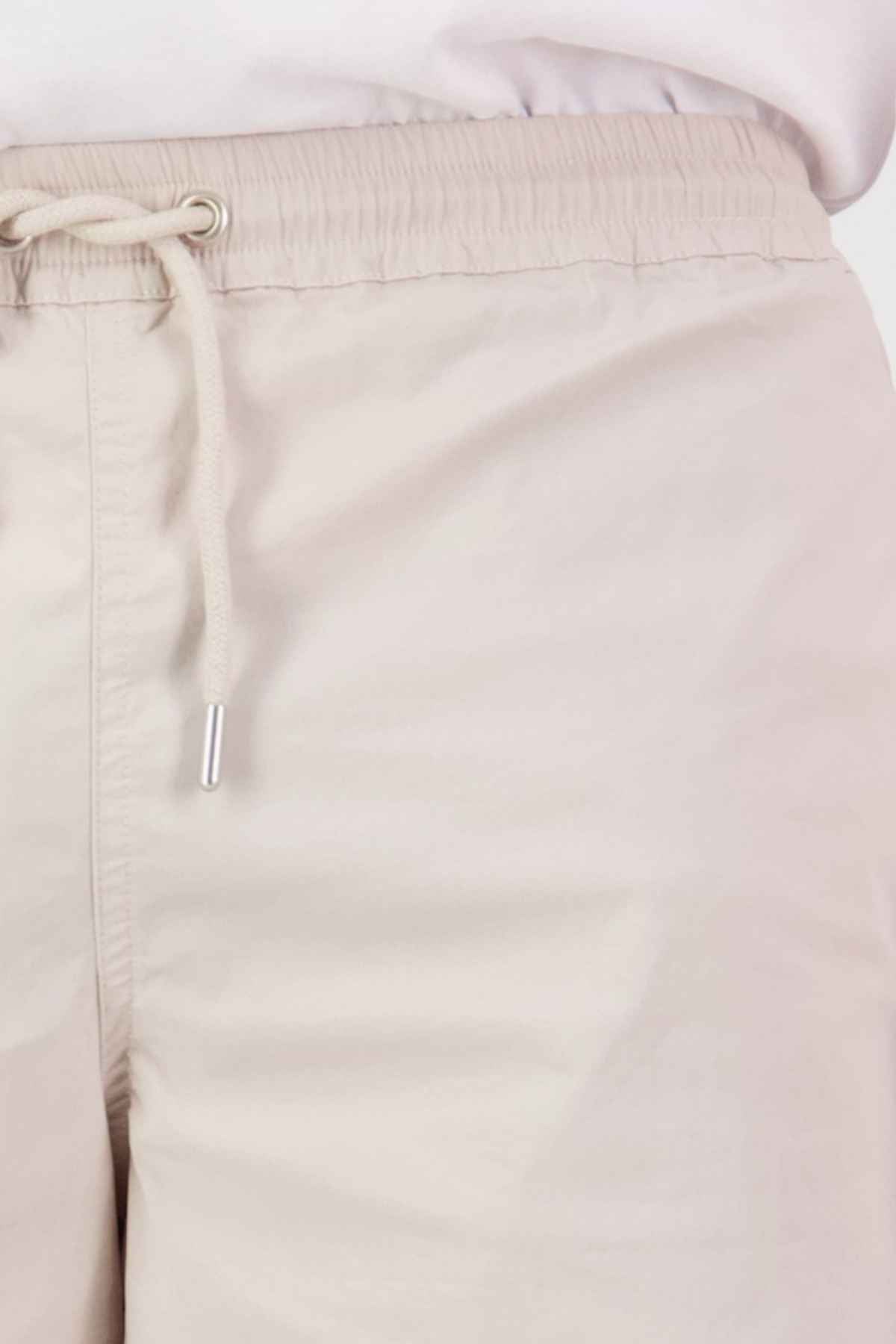 Close-up of light beige drawstring pants made from a soft cotton blend, featuring a lightweight fabric and an uncomplicated, relaxed fit. The elastic waist drawstring is loosely tied, exuding a casual and comfortable style similar to that of the Swanndri Frankton Short.