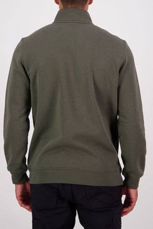 Someone stands against a plain light background, facing away from the camera, wearing an olive green Swanndri Fundamentals Quarter Zip made with recycled polyester and black pants.