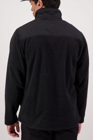 A person wearing a black Swanndri High Rock Hybrid Fleece Pullover made from recycled polyester and a black cap is photographed from the back against a plain light background.