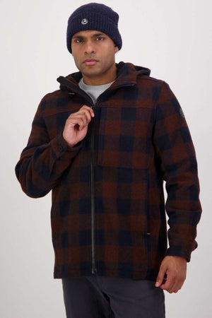 A man zips up his Swanndri Hudson Hoodie, featuring a navy and brown check pattern, while standing against a plain light background and wearing a navy knit beanie.