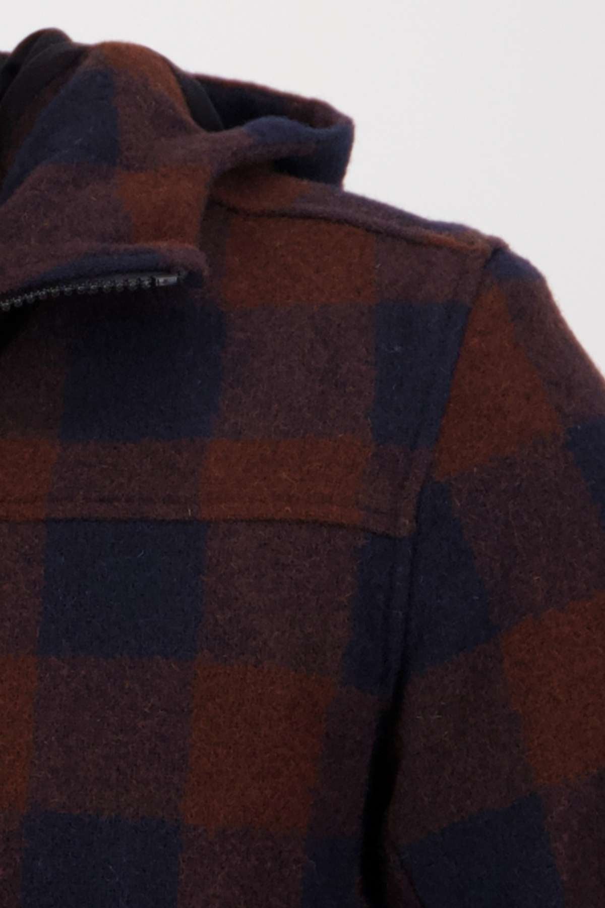 Close-up of the Swanndri Hudson Hoodie, made from New Zealand wool, showcasing a dark red and navy blue plaid pattern on the shoulder, collar, and upper sleeve against a plain background.
