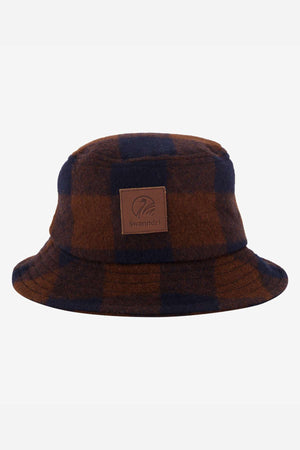 The Swanndri Kaimai Wool Bucket Hat showcases a brown and navy plaid design with a leather patch featuring the iconic "Swanndri" logo, perfect for outdoor adventures against a light gray backdrop.