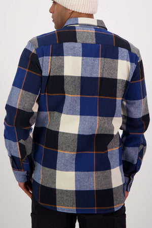 Someone is shown from the back against a plain light background, wearing the Swanndri Lowcliffe Shacket—a 100% cotton, classic fit shirt—in blue, black, gray, and white checks with a white knit beanie.