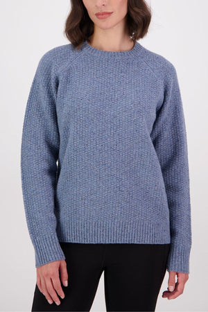 A woman wearing the Swanndri Lyttelton Womens Waffle Crew in light blue and black pants stands against a plain white background.