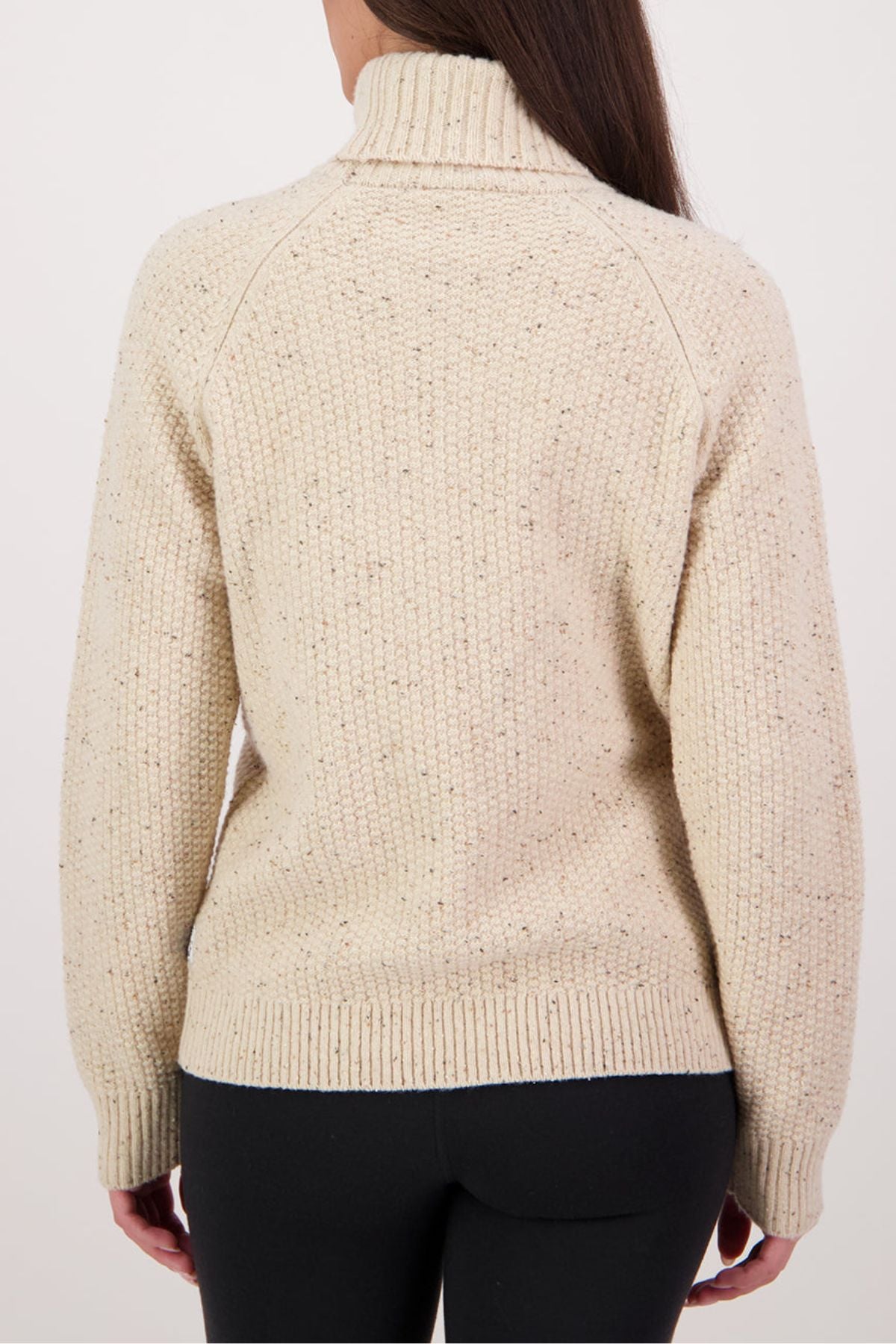 A person with long brown hair is seen from the back, wearing a cream Swanndri Lyttelton v2 Roll Neck Knit sweater with a high collar and black pants against a plain, light background.