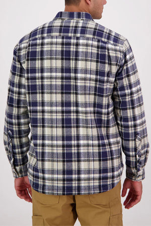 A man with short hair and tan pants stands facing away, wearing the Swanndri Morven Sherpa Long Sleeve Shirt in a blue, white, and gray plaid. The shirt is made from 100% cotton and set against a plain light background.