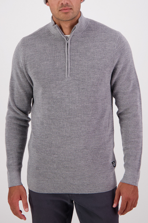 A man wearing a Swanndri Otahu River Quarter Zip Merino Knit in light grey and dark pants stands against a plain white background.