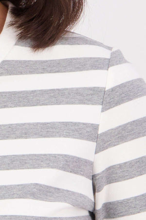 Close-up of a person wearing the Swanndri Papamoa Stripe Long Sleeve Tee, featuring horizontal gray and white stripes, a relaxed fit, and a white collar. Part of the personβs hair is visible at the top.