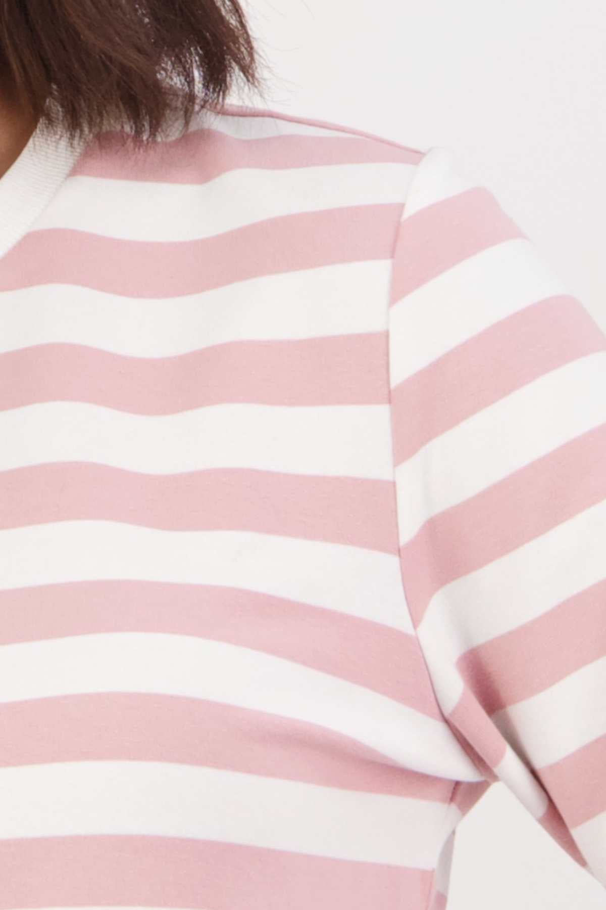 Close-up of someone wearing the Swanndri Papamoa Stripe Long Sleeve Tee in pink and white stripes. This relaxed fit top covers the shoulder and upper chest, ideal for everyday outfits, set against a plain background.