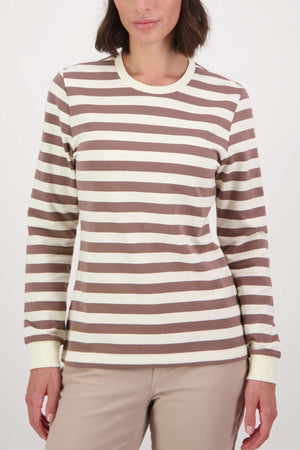 A person wearing a Swanndri Papamoa Stripe Long Sleeve Tee in brown and white, made from cotton elastane with a round neckline, stands against a plain background, complementing their shoulder-length hair and beige pants.