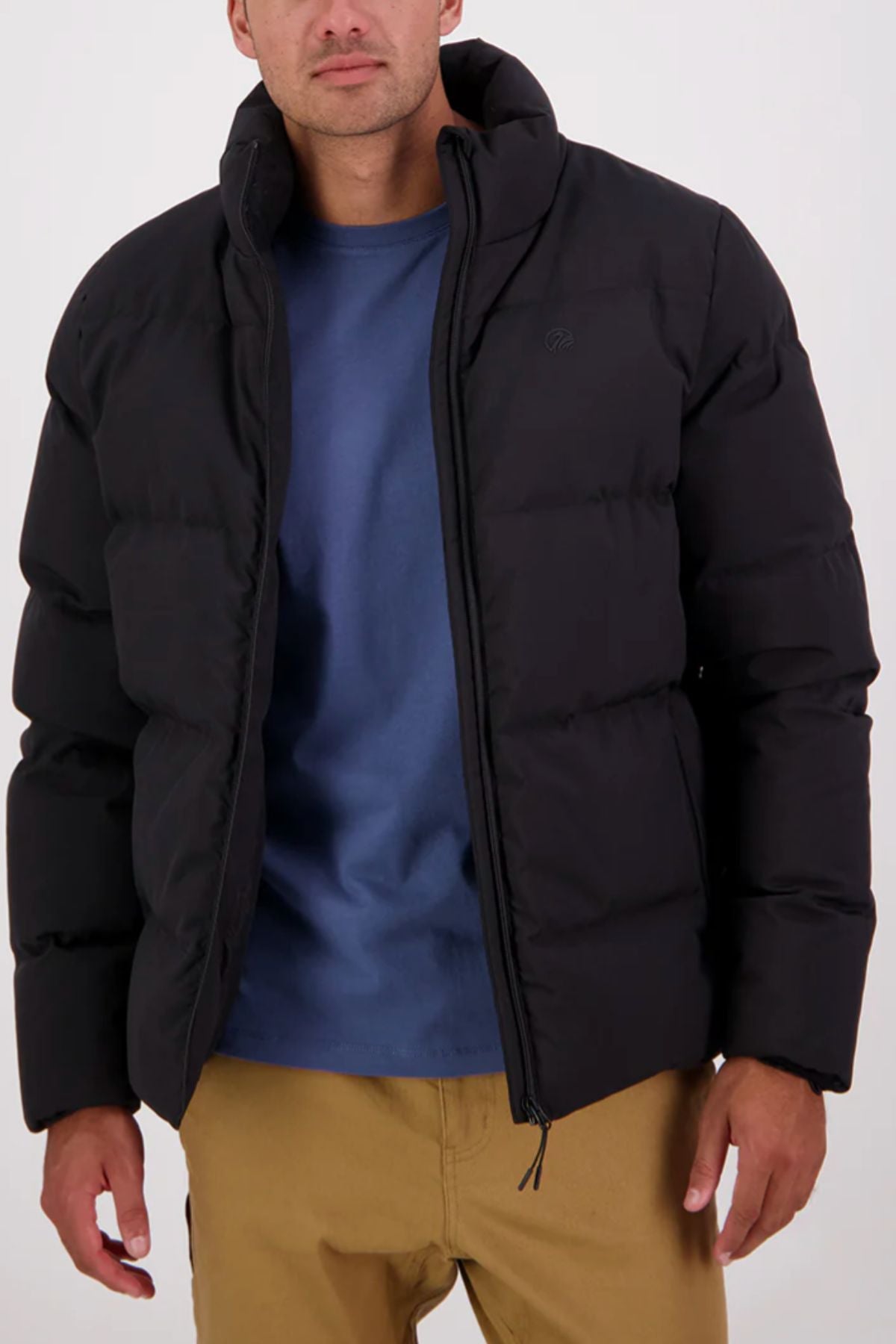 A person models the Swanndri Plume Mens Down Jacket, unzipped over a blue shirt and tan pants, standing against a plain light background with hands relaxed—perfect outerwear for outdoor adventures.