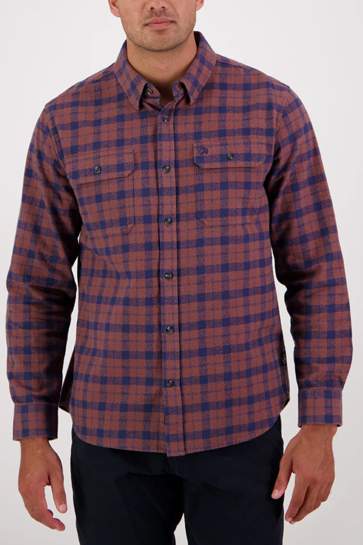 A man wears the Swanndri Port Road Shirt, a long-sleeve, button-up cotton twill shirt in a brown and blue yarn-dyed check with two chest pockets, shown from shoulders to hips against a plain background.