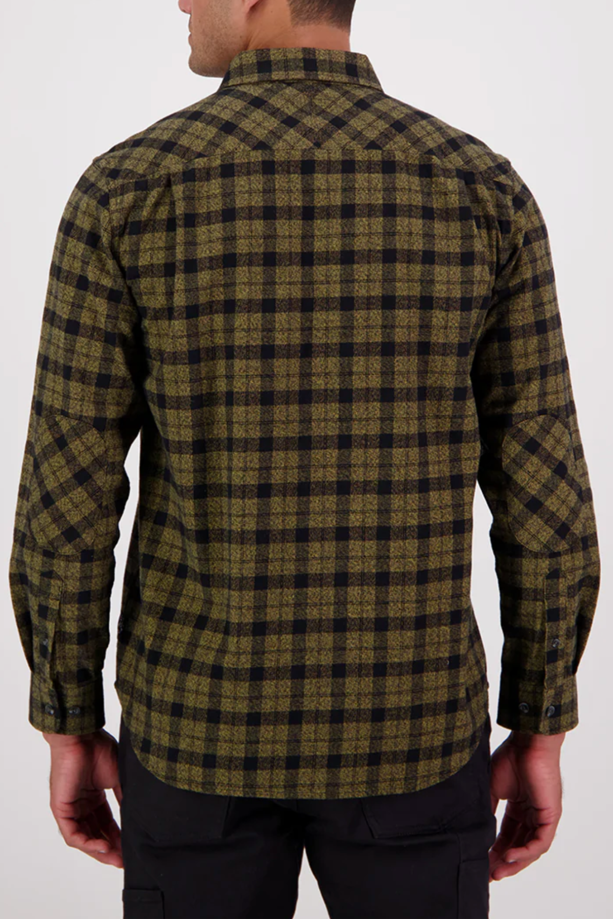 A man, seen from behind, wears the Swanndri Port Road Shirt—crafted from heavyweight cotton twill in an olive green and black yarn-dyed check—with long sleeves, a collar, buttoned cuffs, and black pants.