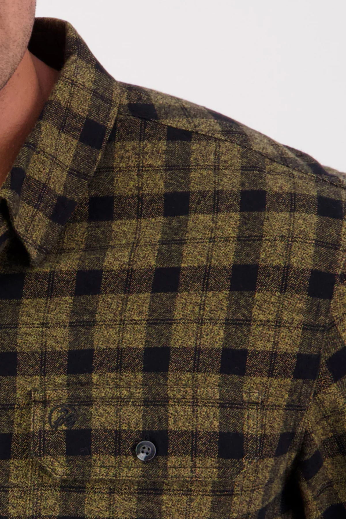 Close-up of the Swanndri Port Road Shirt in green and black plaid heavyweight cotton twill, showing its collar, button, partial chest pocket, and detailed yarn-dyed check texture.
