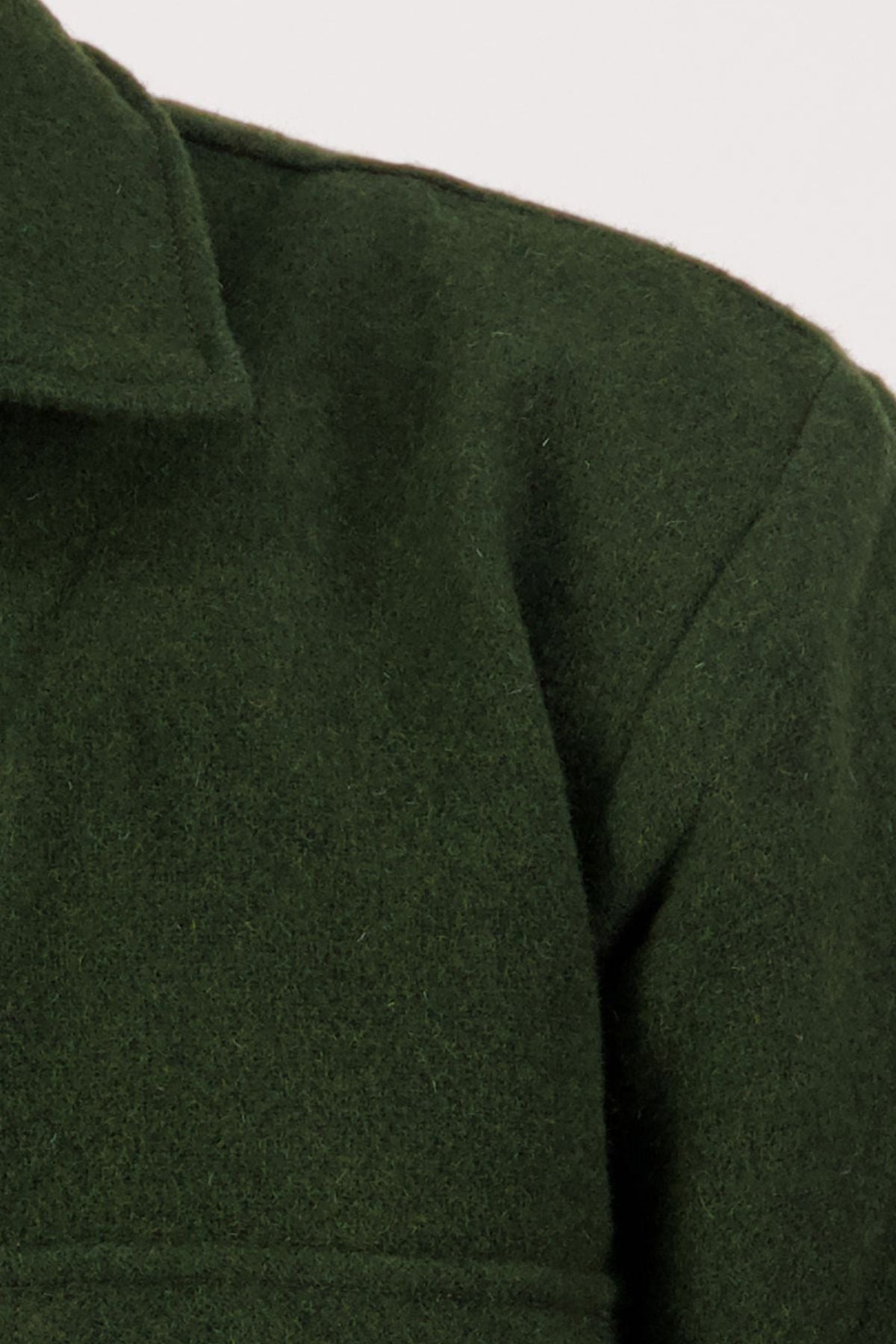 Close-up of the upper section of a dark green Swanndri Ranger Bush Shirt, highlighting the collar, shoulder seam, and fabric texture against a plain light background.