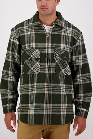 A man stands against a plain white background wearing an oversized green and white plaid zip-up shirt jacket inspired by the Swanndri Ranger Bush Shirt, featuring two chest pockets, paired with tan pants.