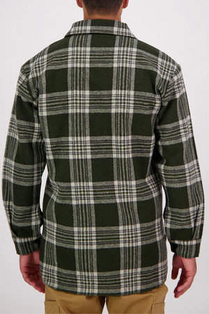 A person wearing a green, white, and black Swanndri Ranger Bush Shirt with an oversized plaid design stands facing away from the camera. The long-sleeve shirt is paired with tan pants against a plain white background.
