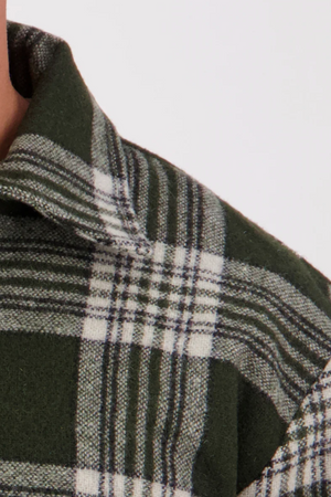 Close-up of the Swanndri Ranger Bush Shirt collar and shoulder in green and white plaid, highlighting the fabric texture and intersecting lines. Only part of the wearer’s neck and shoulder is visible.