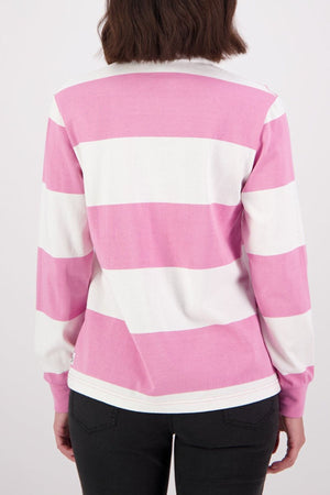 A person with shoulder-length brown hair is seen from behind wearing the Swanndri Ridgeway Womens Rugby, a 100% cotton long-sleeve shirt with wide pink and white stripes, paired with black pants.