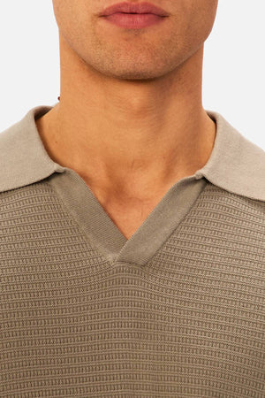 Close-up of a person wearing the Industrie The Alicante Polo in textured beige with a v-neckline and soft collar, showing only the lower half of their face and neck.
