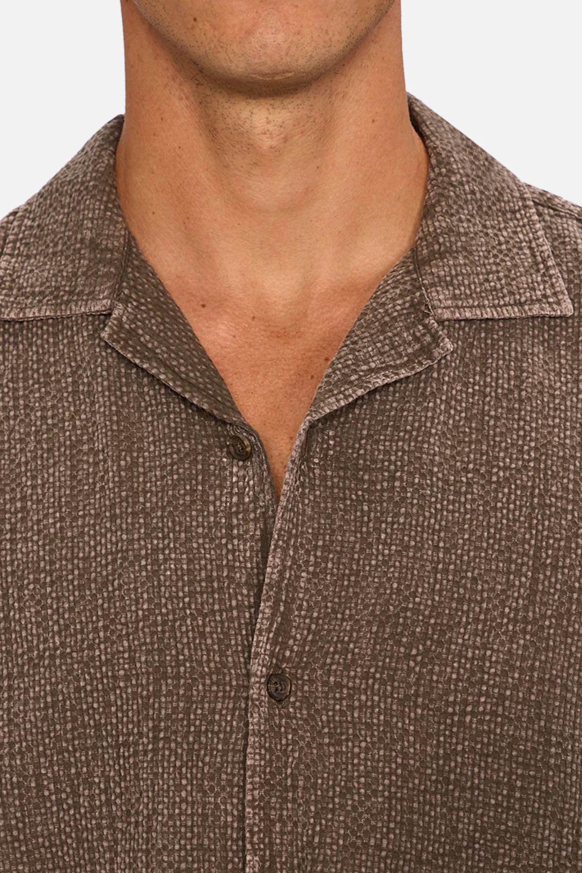 Close-up of a person wearing the Industrie The Canyon Short Sleeve Shirt in textured brown with a spread collar, cropped to show just the neck, lower face, and upper chest.