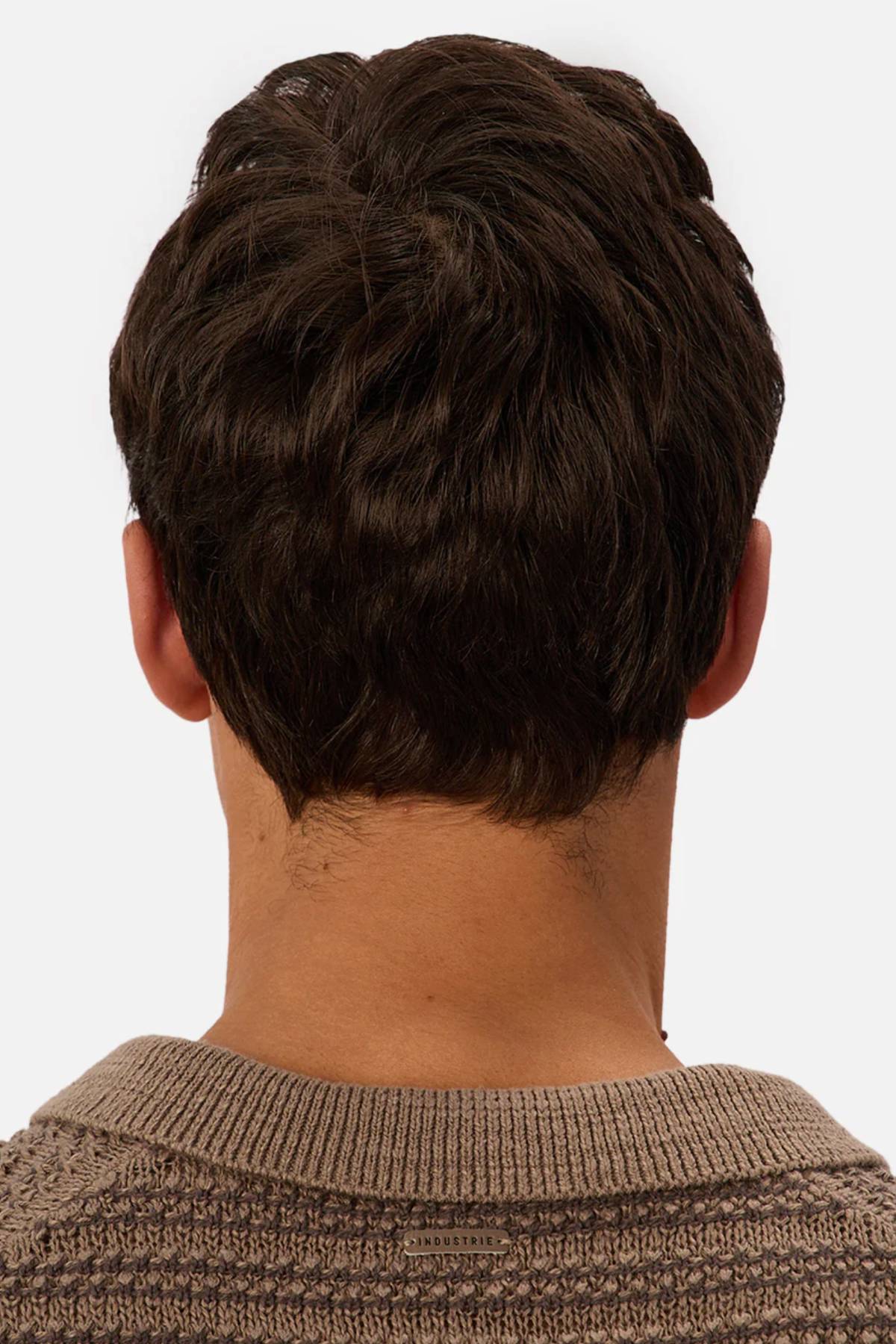 Seen from behind, a person with short, dark brown hair wears the Industrie The Matera Polo, a heavyweight knitted polo in light brown that stands out against a simple, light-colored background.