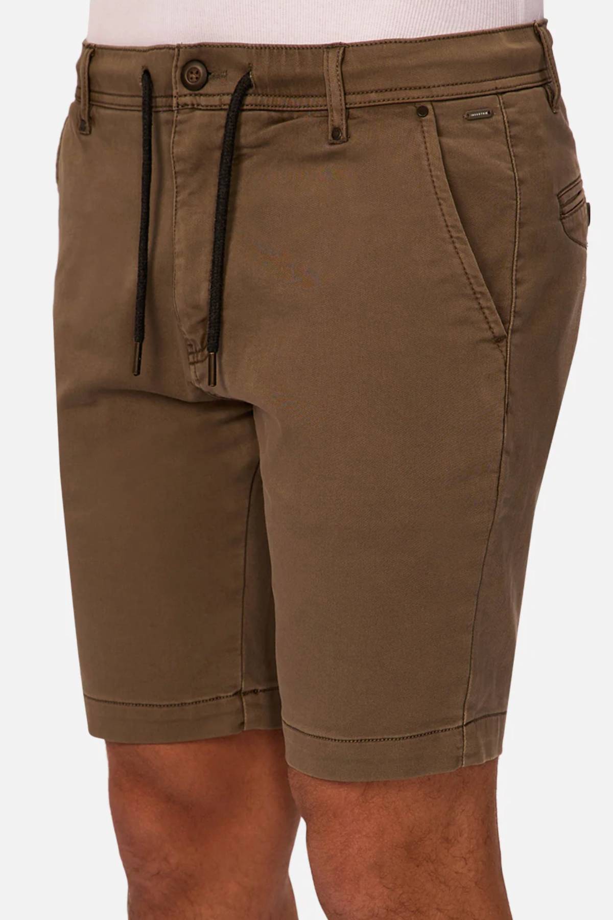 A person wearing Industrie The New Drifter Cuba Short in brown, knee-length with side and back pockets, styled with a white top. The image highlights the slim fit from waist to above the knees—ideal as men's everyday shorts.