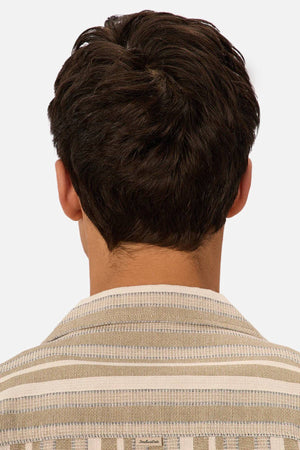 A person with short, dark brown hair is seen from behind wearing the Industrie The Textured Livorno Short Sleeve Shirt in beige and white stripes. The relaxed fit shirt stands out against a plain, light-colored background.