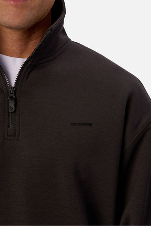 A close-up of a person wearing the Industrie The Tech Staunton Track Top over a white shirt, highlighting the zipper, collar, and subtle embroidered branding on the chest.