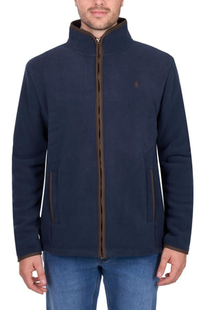 A man wearing a navy blue Thomas Cook Adrian Jacket, a heavyweight fleece with brown trim, stands with hands at his sides in blue jeans against a plain white background.