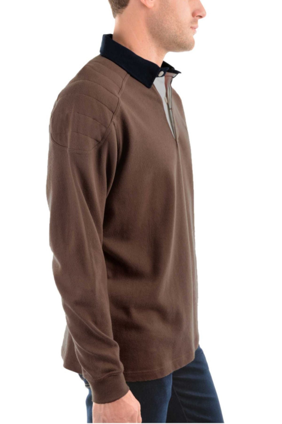 A man in the Thomas Cook Bill Rugby—a long-sleeved brown cotton shirt with a black collar—stands in profile against a white background.
