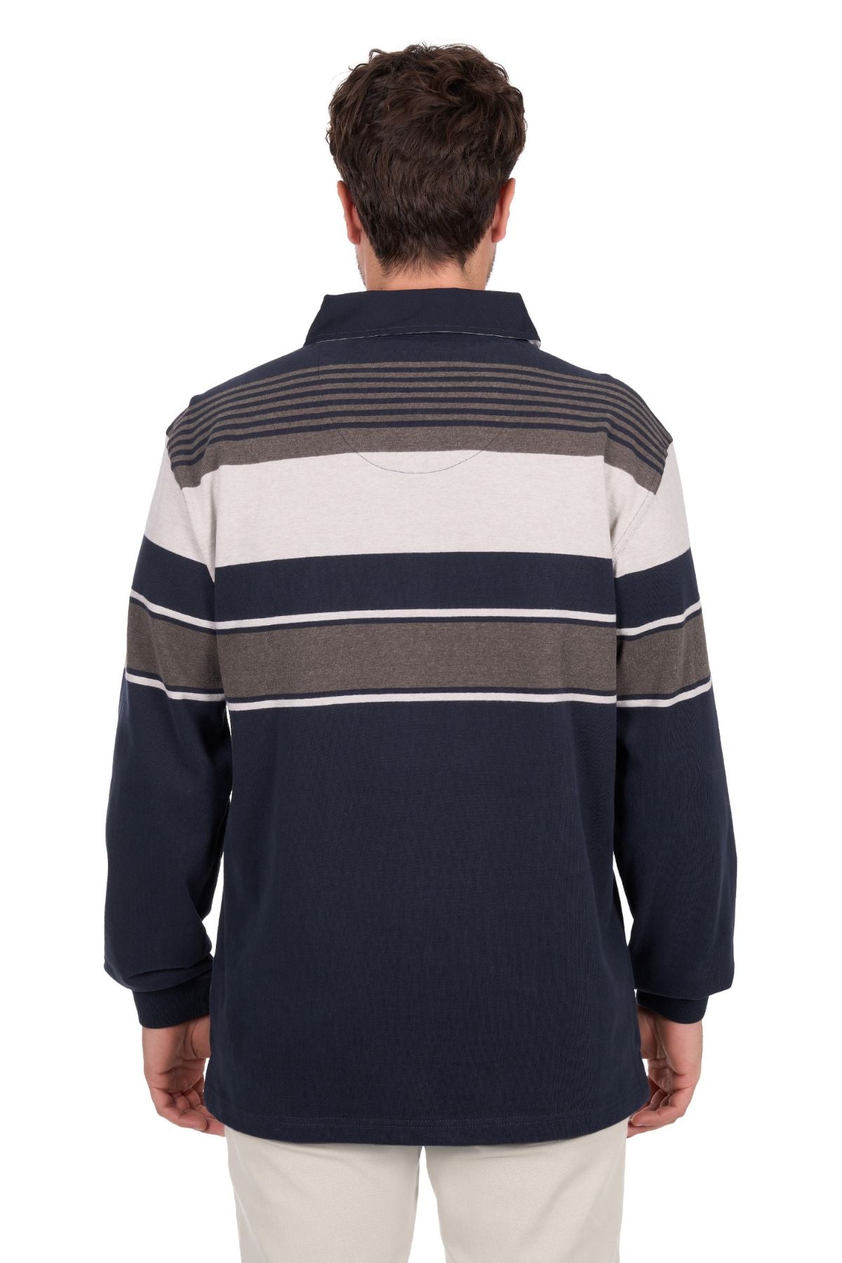 A man with short dark hair and light pants stands with his back to the camera, wearing the Thomas Cook Bryan Stripe Rugby—a long-sleeve, collared shirt with horizontal navy blue, gray, and white stripes.