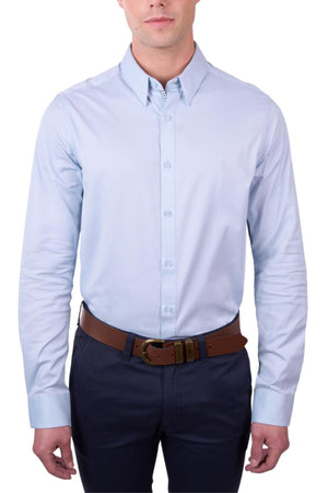 A man wearing a light blue Thomas Cook Callum Tailored Shirt in premium woven fabric, dark pants, and a brown belt stands against a white background. His face is partially visible and his arms are relaxed at his sides.