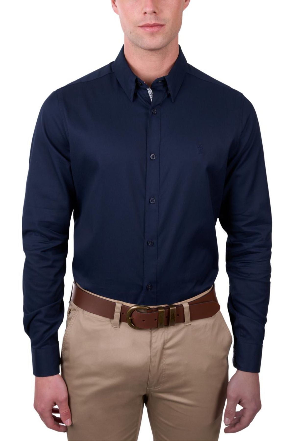 A man wears the Thomas Cook Callum Tailored Shirt in dark navy, tucked into tan khaki pants with a brown leather belt, standing against a plain white background.