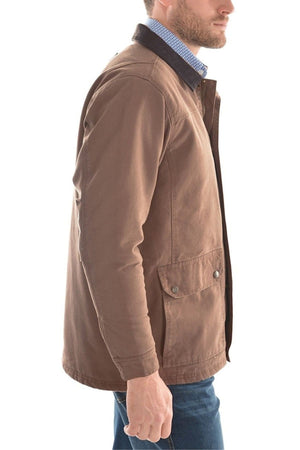 A man wearing the Thomas Cook Canvas Jacket with a leather collar over a blue checkered shirt and blue jeans, standing sideways against a white background.