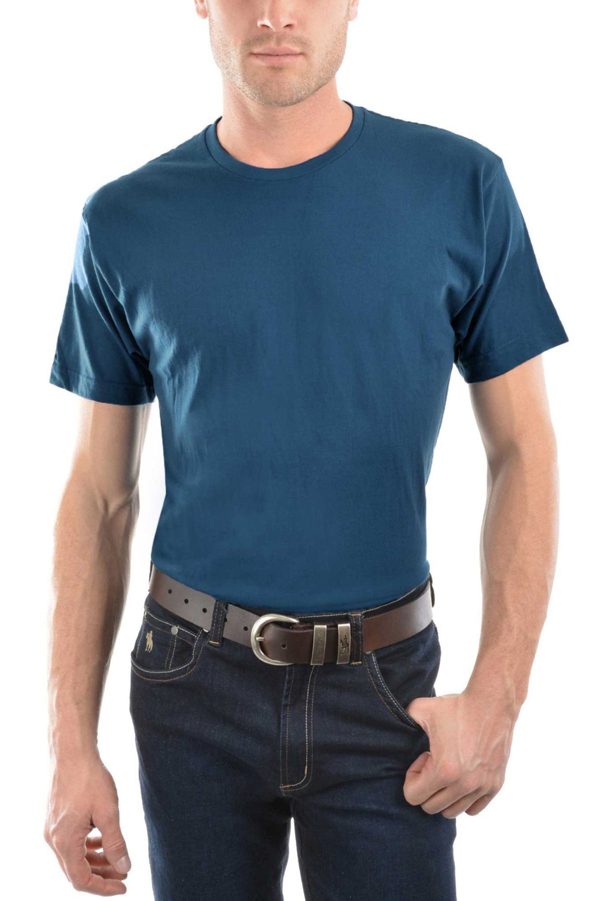 A man wears a Thomas Cook Classic Fit Tee in plain blue, dark jeans, and a brown belt, standing with one hand in his pocket against a white background. Crafted from 100% combed cotton, this tee offers all-day comfort. His face is partially out of frame.