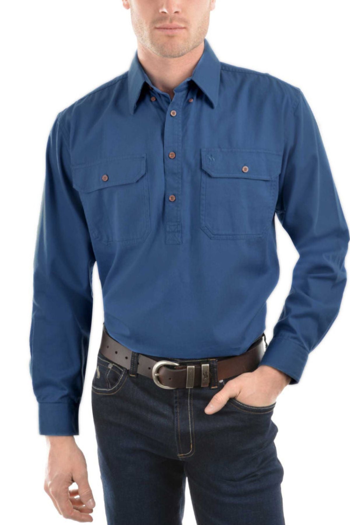 A man wearing the Thomas Cook Heavy Drill Half Placket Shirt, a long-sleeve blue work shirt with two chest pockets, paired with dark jeans and a black belt, stands against a white background. His face is partially out of frame.