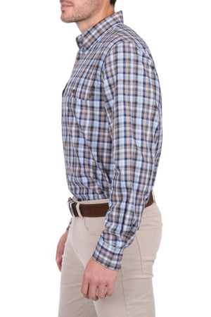 A man stands in profile against a white background wearing the Thomas Cook Jonathan Shirt, a blue and brown plaid 100% cotton shirt, paired with beige pants and a brown belt.