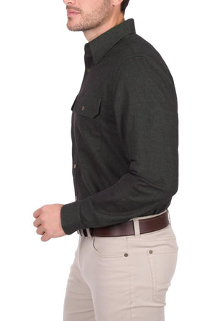 A man is shown from the side against a white background, wearing a dark green Thomas Cook Keith Thermal Shirt and light beige pants with a brown belt. His face is partially out of frame.