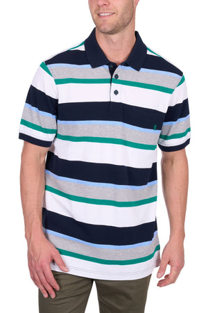 A man wears the Thomas Cook Paul Polo, a cotton pique shirt with multi-colour stripes in navy, white, grey, green, and light blue. He smiles with his right hand by his side and his left hand touching his thigh.