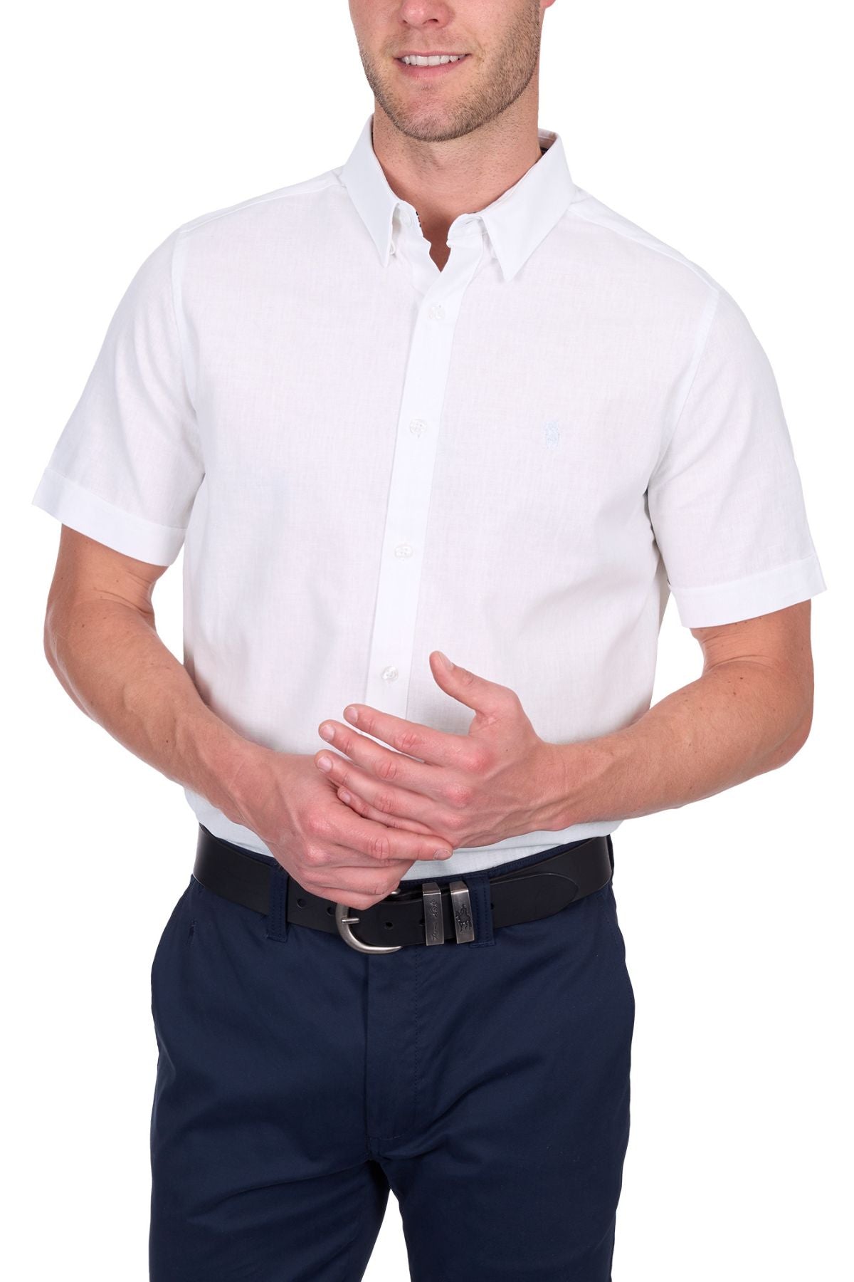 A man wears the Thomas Cook TC Linen Short Sleeve Shirt in white, tucked into navy blue pants with a black belt, standing against a white background. His face is partially out of frame.