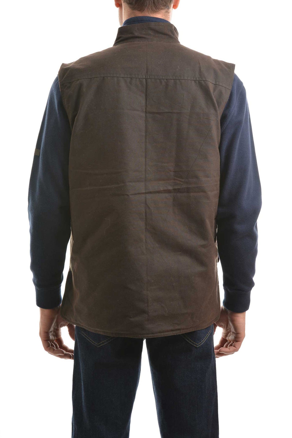 Someone is shown from the back against a white background, wearing a Thomas Cook High Country Oilskin Vest in dark brown over a navy blue long-sleeve shirt and blue jeans.