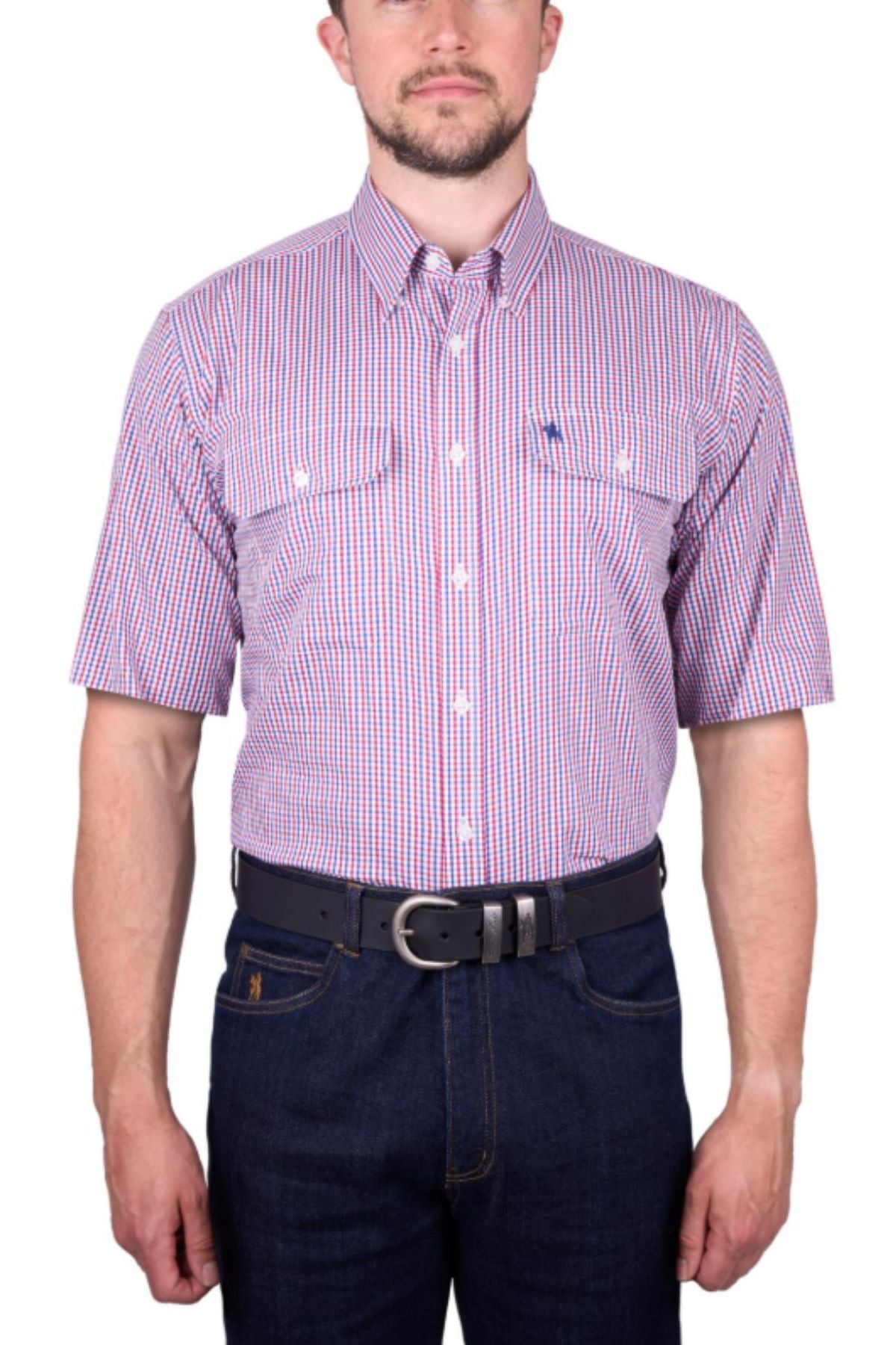 A man wears the Thomas Cook Wentworth Short Sleeve Shirtโclassic fit, 100% cotton, in a red, white, and blue checkered patternโwith dark blue jeans and a black belt, standing against a plain white background.