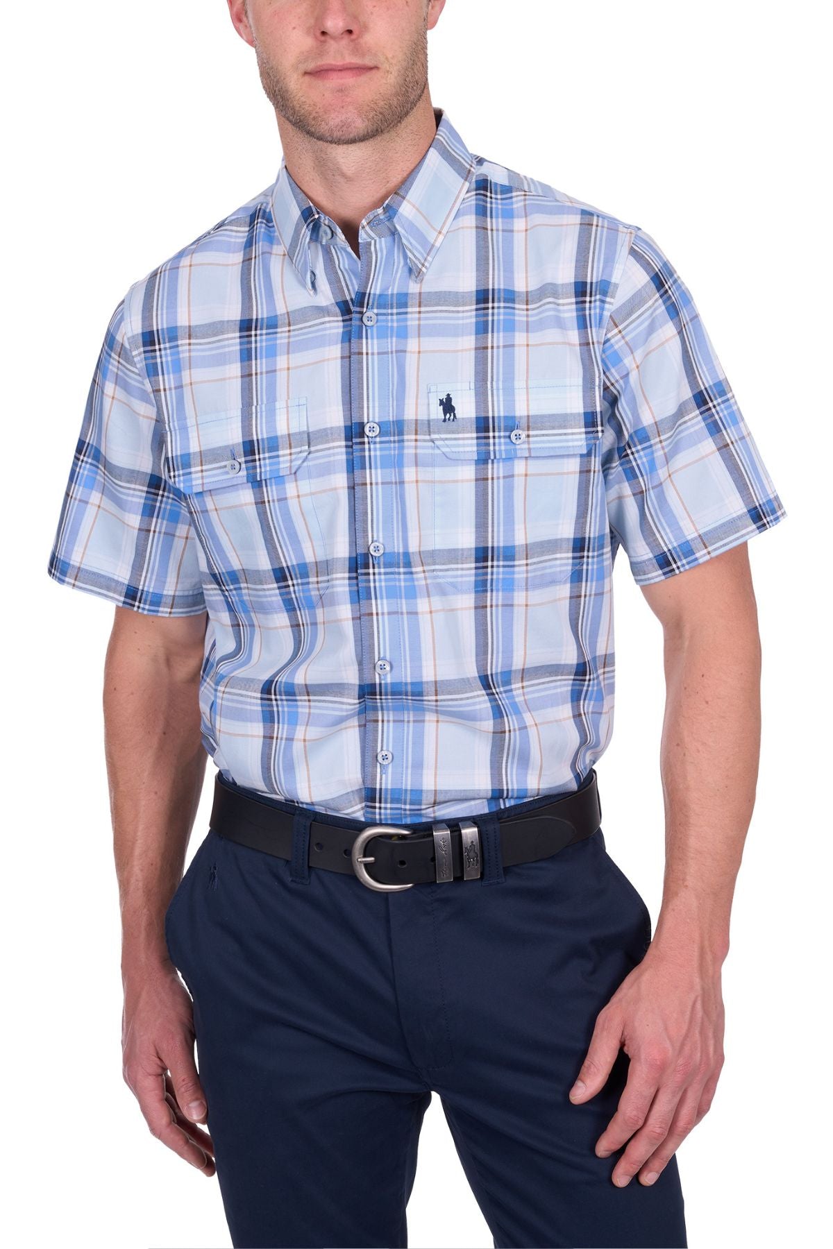 A man wears the Thomas Cook Brian Short Sleeve Shirtβa light blue plaid, 100% cotton, collared shirt with a small chest logoβpaired with dark blue pants and a black belt. The background is white.