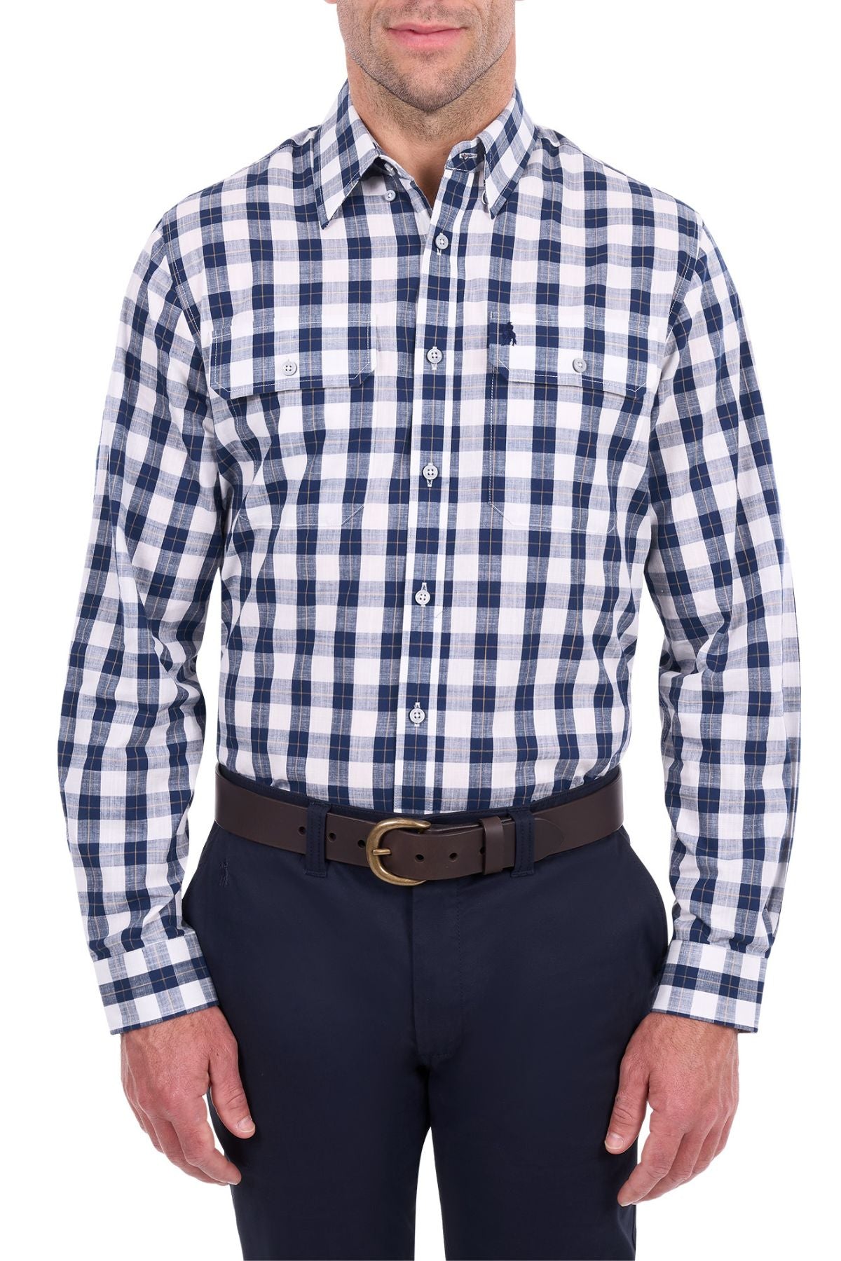 A man stands against a white background, his head partially out of frame, wearing the Thomas Cook Ezra Shirt—a blue and white cotton check workwear shirt—paired with dark trousers and a dark brown belt.